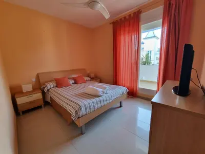 a bedroom with a bed with red curtains and a television at Ático en Costa Ballena con Barbacoa, Aire Acondicionado y WIFI in Costa Ballena