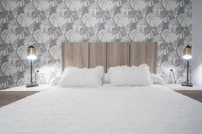 a bedroom with a large white bed with a floral wallpaper at Apartamento La Magnolia de Cádiz in Cádiz