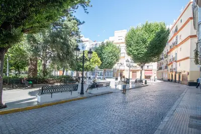 a cobblestone street with benches and trees and buildings at Apartamento La Magnolia de Cádiz in Cádiz