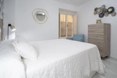 a white bedroom with a white bed and a dresser at Apartamento La Magnolia de Cádiz in Cádiz