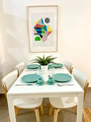 a white dining room table with white chairs and a painting at Carmen viejo 12 in Sanlúcar de Barrameda