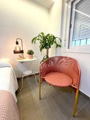 a bedroom with a chair and a table and a window at Carmen viejo 12 in Sanlúcar de Barrameda