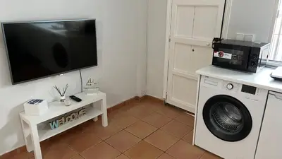 a living room with a washing machine and a tv at Acogedor estudio junto playa, El Manantial in El Puerto de Santa María
