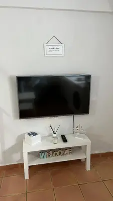 a flat screen tv on a wall with a white table at Acogedor estudio junto playa, El Manantial in El Puerto de Santa María