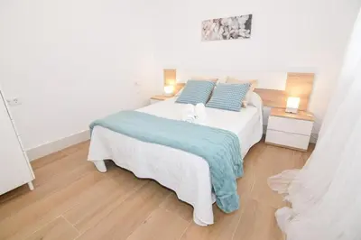 a bedroom with a large white bed with blue pillows at Apartamentos Atlantida in Chipiona