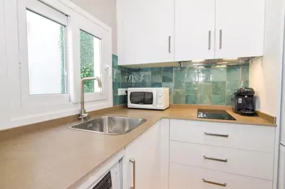 a kitchen with white cabinets and a sink and a microwave at Apartamentos Atlantida in Chipiona