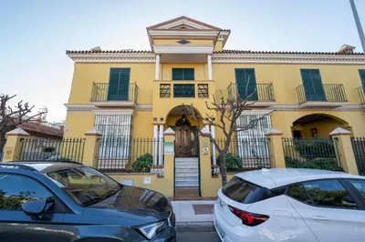 two cars parked in front of a yellow house at VILLA CAPITAN in Sanlúcar de Barrameda