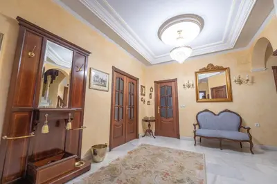 a hallway with wooden doors and a blue chair at VILLA CAPITAN in Sanlúcar de Barrameda