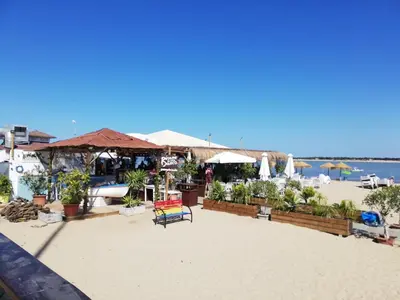 a beach with chairs and umbrellas and the ocean at CASA PALACIO CABALLEROS 7 con Parking in Sanlúcar de Barrameda