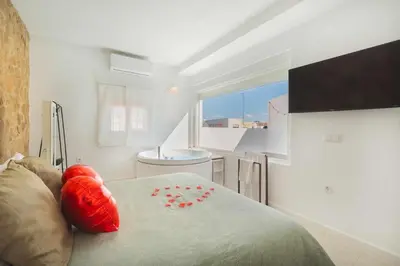 a bedroom with a bed with red pillows on it at Jacuzzi Amanecer de Plata Decoración Romántica in Chiclana de la Frontera