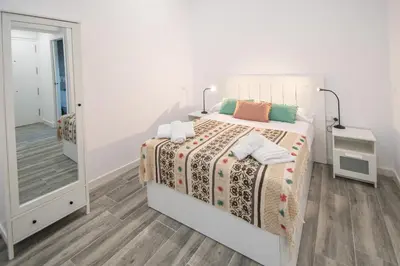 a white bedroom with a bed and a mirror at Estudio Al Sur de Cádiz in Cádiz
