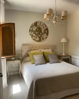 a bedroom with a bed with two tables and a chandelier at Ático San Juan in Sanlúcar de Barrameda