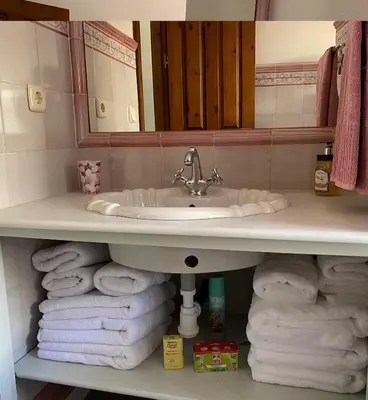 a bathroom with a sink and a pile of towels at Ático San Juan in Sanlúcar de Barrameda