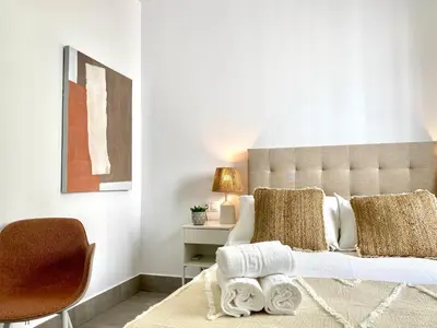 a bedroom with a large bed and a chair at Apartamentos Casa Macías in Cádiz