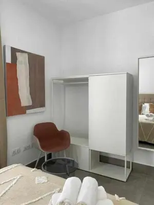 a bedroom with a bed and a chair and a mirror at Apartamentos Casa Macías in Cádiz