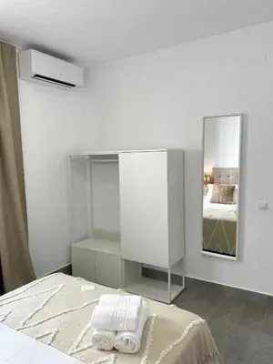a white room with a bed and a mirror at Apartamentos Casa Macías in Cádiz