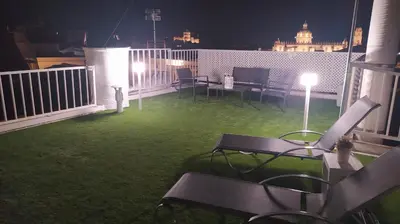 a patio with chairs and a table on a balcony at night at Sherryflat Luna in Jerez de la Frontera