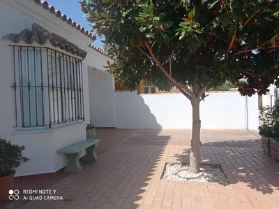 a bench next to a building with a tree at VILLA SANTA CLARA in Chiclana de la Frontera