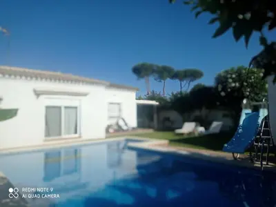a swimming pool in front of a house at VILLA SANTA CLARA in Chiclana de la Frontera
