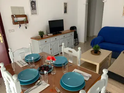 a living room with a dining room table with blue plates at Apartamento Wifi, Garaje Centro y playa in Chipiona