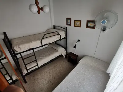 a room with two bunk beds and a fan at Apartamento Wifi, Garaje Centro y playa in Chipiona