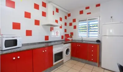 a kitchen with red cabinets and a white refrigerator at Casa Enrique in Cádiz
