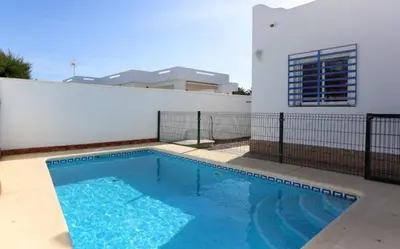 a swimming pool in front of a house at Casa Juani in Conil de la Frontera