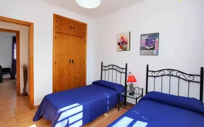 a bedroom with two beds with blue sheets and a door at Casa Juani in Conil de la Frontera