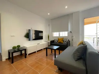 a living room with a couch and a flat screen tv at El Mirador del Coto, Apartamentos Living Sur in Sanlúcar de Barrameda