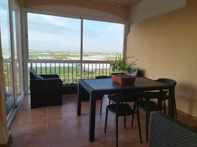 a dining room with a table and chairs and a large window at El Mirador del Coto, Apartamentos Living Sur in Sanlúcar de Barrameda