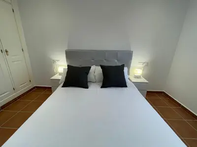a bedroom with a large white bed with two lamps at El Mirador del Coto, Apartamentos Living Sur in Sanlúcar de Barrameda