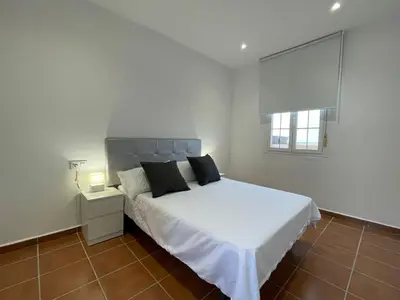 a white bedroom with a white bed and a window at El Mirador del Coto, Apartamentos Living Sur in Sanlúcar de Barrameda