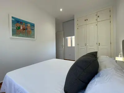 a bedroom with a white bed and a picture on the wall at El Mirador del Coto, Apartamentos Living Sur in Sanlúcar de Barrameda