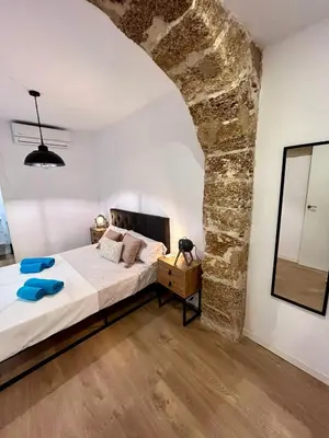 a bedroom with a bed and a stone wall at GATU PREMIUM Villa La Pepa in Cádiz