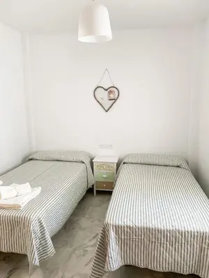 two beds in a bedroom with a heart sign on the wall at Apartamento Sol y Sal in Chiclana de la Frontera