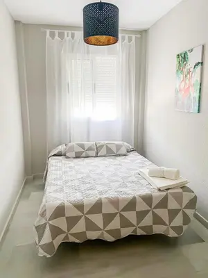a bedroom with a large bed with a window at Apartamento Sol y Sal in Chiclana de la Frontera