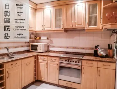 a kitchen with wooden cabinets and a microwave at Apartamento Sol y Sal in Chiclana de la Frontera