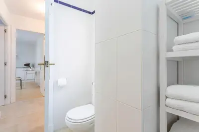 a white bathroom with a toilet and towels at Azvalia - Larga 112 in El Puerto de Santa María