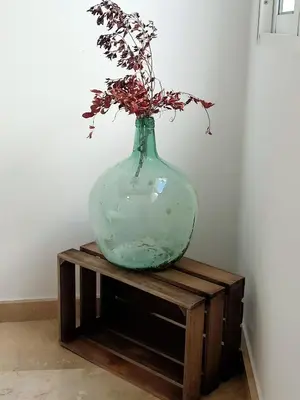 a green vase sitting on a wooden stand with a plant in it at Azvalia - Larga 112 in El Puerto de Santa María