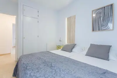 a white bedroom with a large white bed with gray pillows at Azvalia - Larga 112 in El Puerto de Santa María