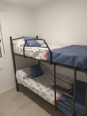 two bunk beds in a room with a bench underneath them at Villa Romadian in Chiclana de la Frontera