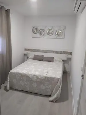 a white bedroom with a bed and two plates on the wall at Villa Romadian in Chiclana de la Frontera