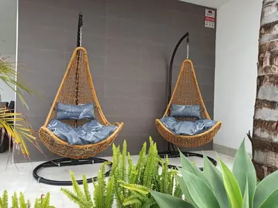 two wicker chairs hanging from a wall with plants at Angkor Wat Village in Puerto Real