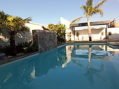 a swimming pool with palm trees and a building at Angkor Wat Village in Puerto Real