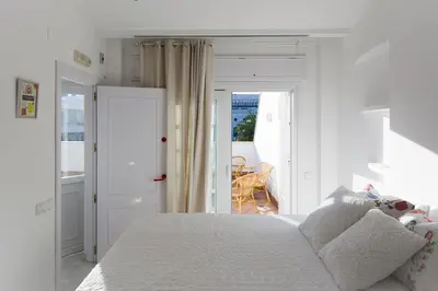 a white bedroom with a bed and a balcony at Ático con terraza Centro Ciudad in El Puerto de Santa María