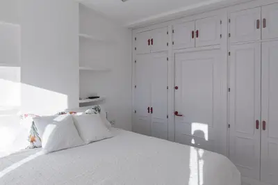 a white bedroom with white cabinets and a bed at Ático con terraza Centro Ciudad in El Puerto de Santa María
