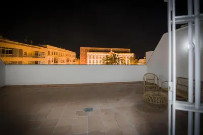 a view of a white wall with buildings at night at Ático con terraza Centro Ciudad in El Puerto de Santa María
