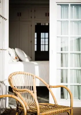 a rattan chair sitting on a porch with a living room at Ático con terraza Centro Ciudad in El Puerto de Santa María