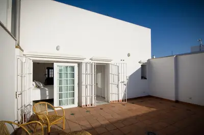 a room with chairs and a white wall at Ático con terraza Centro Ciudad in El Puerto de Santa María
