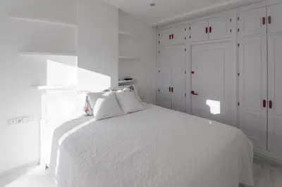 a white bedroom with a white bed and white cabinets at Ático con terraza Centro Ciudad in El Puerto de Santa María